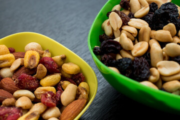 Some peanuts, raisins and nuts in a pot on a dark wooden table 