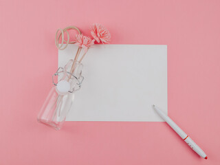 Flowers, notebook and pen.
Flowers in a vase, a blank notebook and a pen lie on a pink background with a place for text in the middle, a close-up top view.