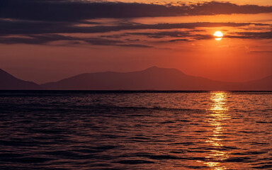 orange fiery sundown sky with some clouds over calm sea, nature background.