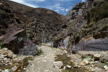 Hiking. View of the footpath along the pure water stream and mountains in a sunny day . The rocky walls texture in the Devils Throat, Jujuy, Argentina. 