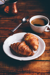 Two Croissants on White Plate and Cup of Black Coffee for Breakfast