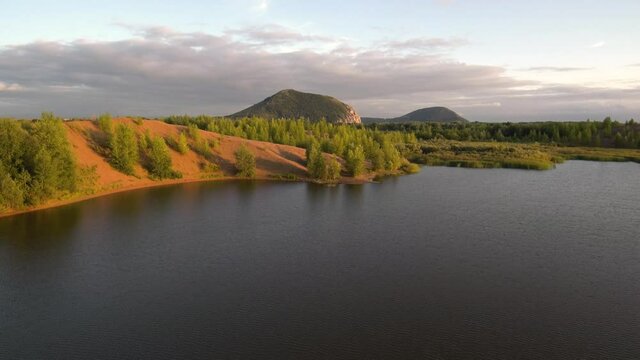 Lake at the site of the extraction of sand and gravel mixture. A mountain of mined gravel.
