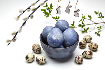 Painted chicken and quail eggs in a bowl and pussy willow branches