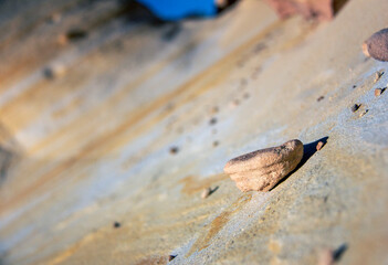 Closeup of sandstone pebble amongst large, striped, orange and yellow formations 