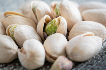 Pistachios close up macro shot featuring an open shell with the a delicious green healthy nut inside.