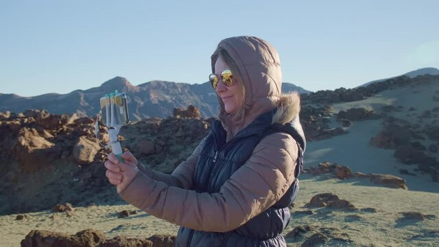 Pretty girl vlogger takes selfies against a Martian landscape in cold and windy weather