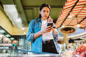 Portrait of concentrated young brunette woman with mobile phone