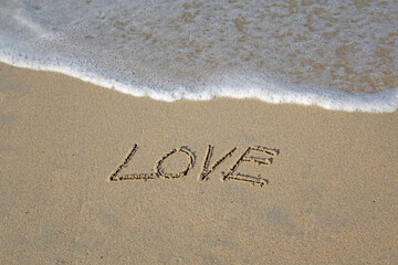 Beach sand messages : Love written in the sand on beach with wave. Concepts photography. Selective focus 