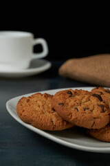 Chocolate Chip cookies with a blured cofee cup at behind and black background