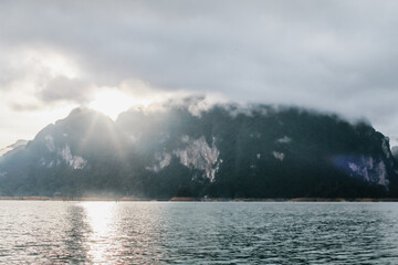 Coastline with cloudy sunset sky, sea and mountains in the Khao Sok National Park, Suratthani Thailand. Nature in twilight period which including of sunrise over the sea. 