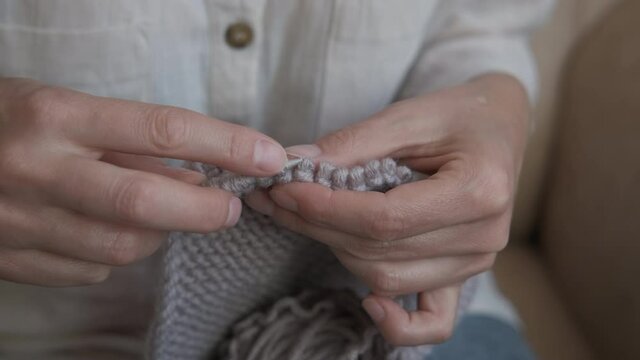 Knitting creation. A woman has a knitting hobby and makes a soft wool clothes.