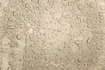 small and large drops of condensation on frosted colored glass