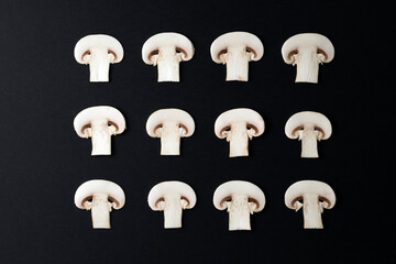 DECORATIVE PATTERN OF MUSHROOMS SLICES ORDERED AND ALIGNED ON BLACK BACKGROUND. VEGAN, VEGETARIAN AND HEALTHY LIFESTYLE CONCEPT. TOP VIEW.