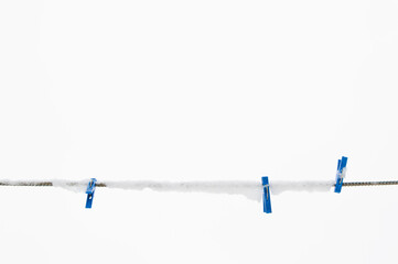 winter background: clothesline covered with snow, several blue clothespins, selective focus