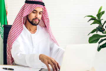 Handsome confident arab businessman working and looking at technology of laptop computer...