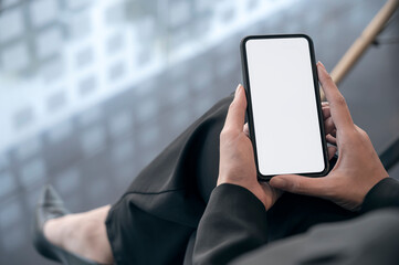 Closeup shot of woman hands holding blank screen smartphone while sitting in office room.