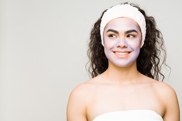 Woman wearing a towel, headband and a beauty mask