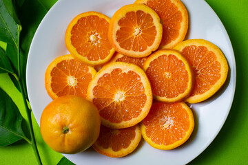 cut oranges on a white plate with green background