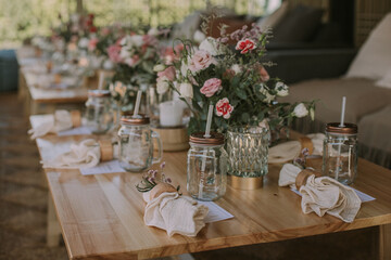 wooden table with personalized glasses, candles and flowers. Decoration for social events.