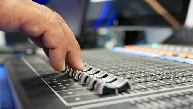 hand adjusting audio mixer in studio.