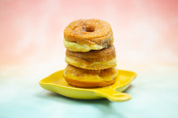 Three sugar coated donuts stacked up on yellow dish