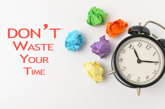 Dont Waste Your time written with alarm clock and paper trash on white background.