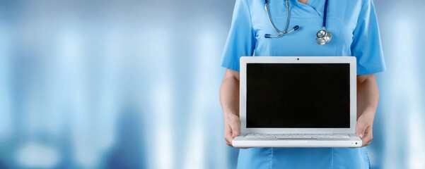 Doctor in white coat holding a laptop computer
