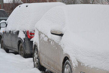 The cars are covered with snow after a snowstorm, bad winter weather, a lot of snow.