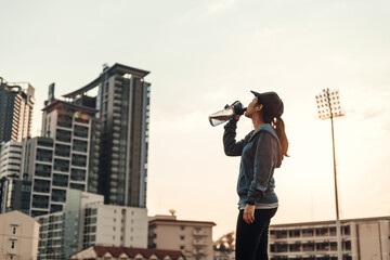 woman athlete thirsty takes a break. she drinking water after running.