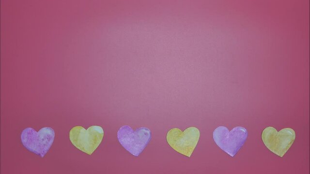 Stop Motion of seamless loop paper cut watercolor hand painted colorful hearts changing color on horizontal border on pink background for Valentine's Day