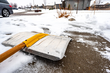 selective focus on the blade of a snow shovel being used to clear concrete