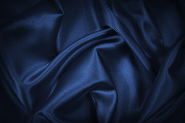 Abstract blue black background. Navy blue silk satin texture background. Beautiful soft wavy folds...