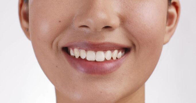 Close up shot of female smiling widely to camera, showing perfect white teeth, slow motion. Oral hygiene concept