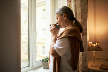Aged people, lifestyle, retirement and loneliness. Indoor shot of elderly female with gray hair...