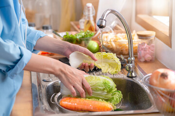 Woman's hands washing a fresh Vegetable to remove pesticides before cooking in kitchen under the tap