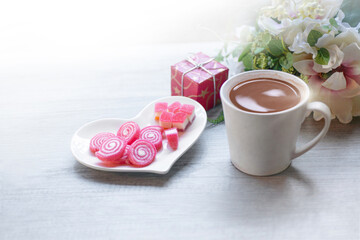 Sweet jelly in heart shaped plate for valentine's day, gift boxes,  bouquets and a cup of chocolate drink on wooden background