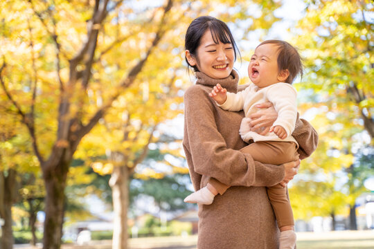 秋の公園で遊ぶ赤ちゃんとママ（号泣）
