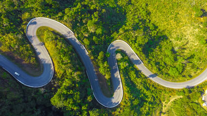 Aerial view of car driving through the forest on country road in mountain.