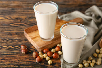 Glasses of tasty hazelnut milk on dark wooden background