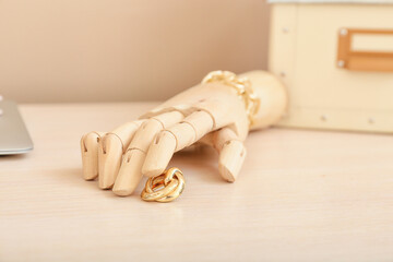Wooden hand with jewelry on table in room
