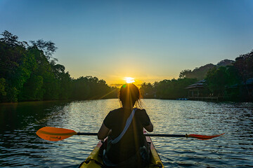 Woman paddling a kayak in the lagoon.manglove between mountains, Thailand.