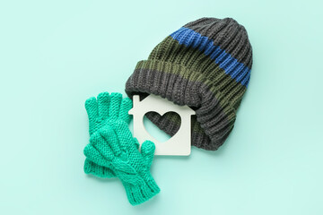 Figure of house and warm clothes on color background. Concept of heating season