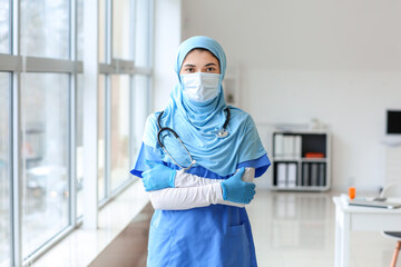 Obraz na płótnie Canvas Portrait of female Muslim doctor wearing protective mask in clinic