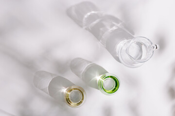 Drinking natural water in colored glass glasses and jug on white background in sunny day. Summer minimal flat lay with hard shadows.