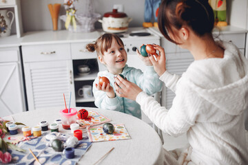 Mother and daughter paint eggs. Family in a kitchen. Preparing for Easter