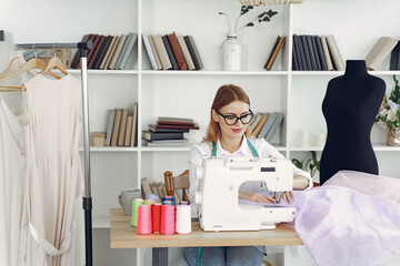 Obraz premium Woman use sewing machine. Designes sew cloth. Blonde in studio.