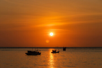 Fototapeta na wymiar Sunset and fishing boat sailing along the sea.