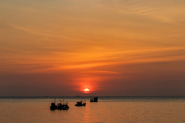 Fototapeta na wymiar Beautiful sunset above the sea and fishing boat sailing along the sea.