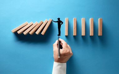 Businessman hand drawing silhouette of a man making a stop gesture to prevent wooden dominos from...