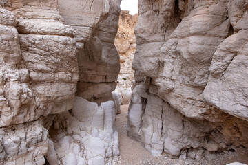 View inside a deep dry canyon in a remote desert region. High white walls of a narrow canyon, rock formations of unusual shapes.